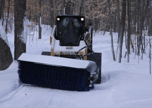 cat skid steer pulling power angle broom front view still